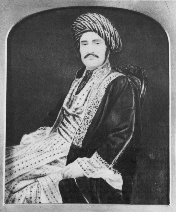 Black and white Portrait of Hormuzd Rassam in traditional Assyrian dress. He is sitting and looks directly at the camera. He wears embroidered garments and a turban.